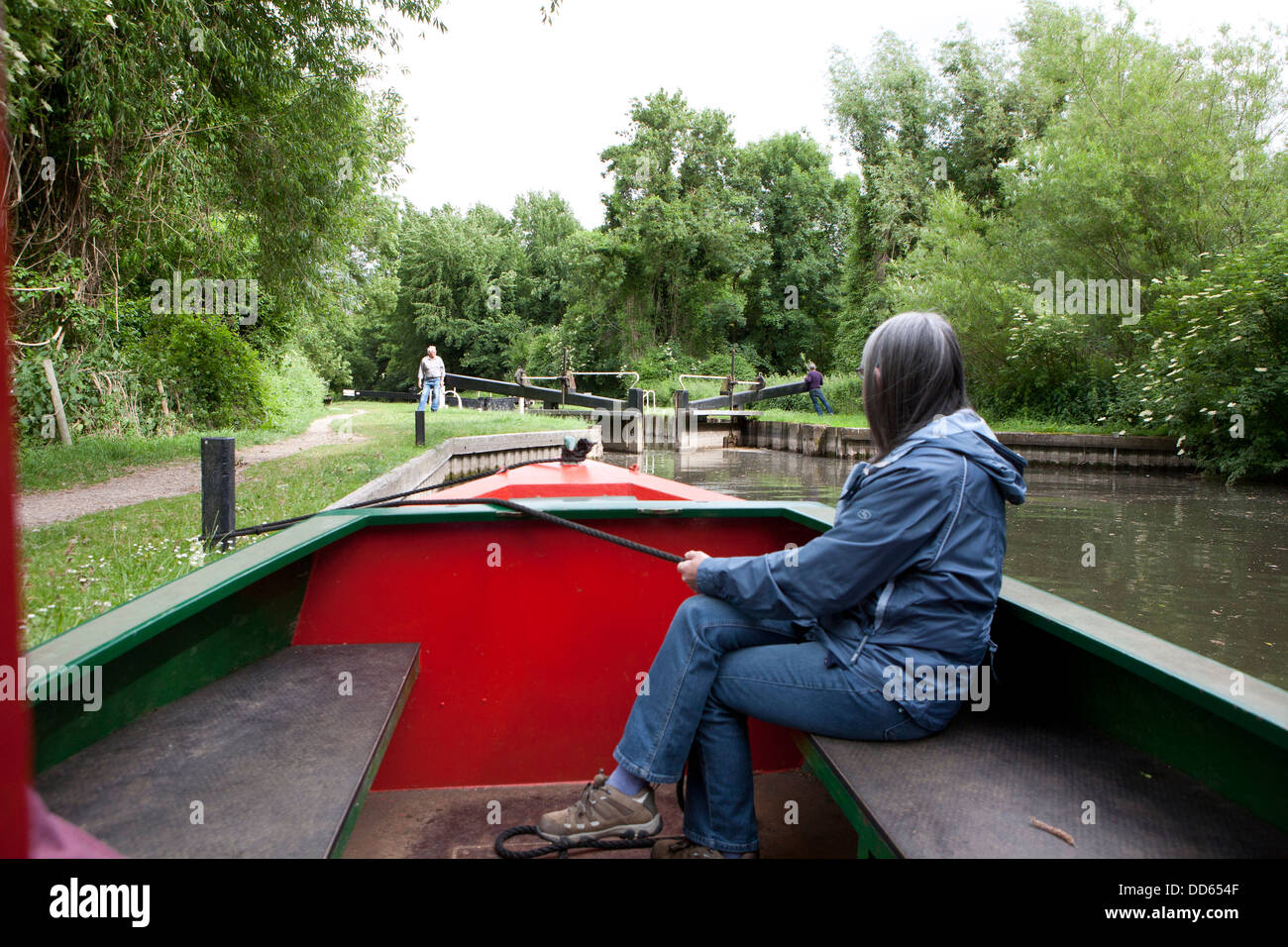 Eine Frau mit einem Seil, einem schmalen Boot (Barge) zu sichern, während eine Sperre in der Ferne geöffnet wird. Stockfoto