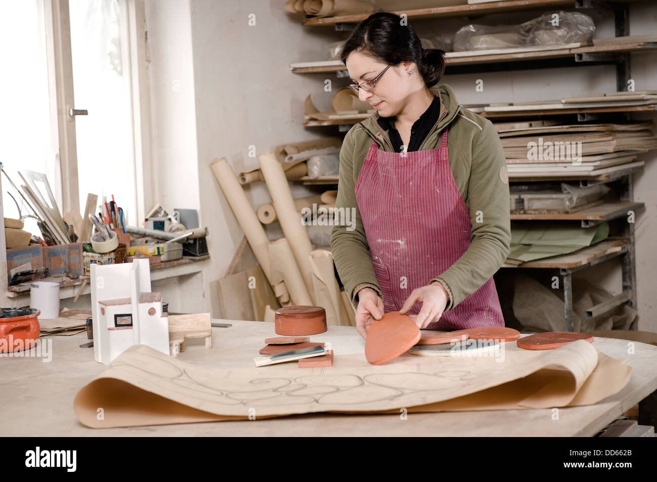 Deutschland, Bayern, Mitte Erwachsene Frau, die Aufsicht über die Farbe der Fliesen in Werkstatt Stockfoto