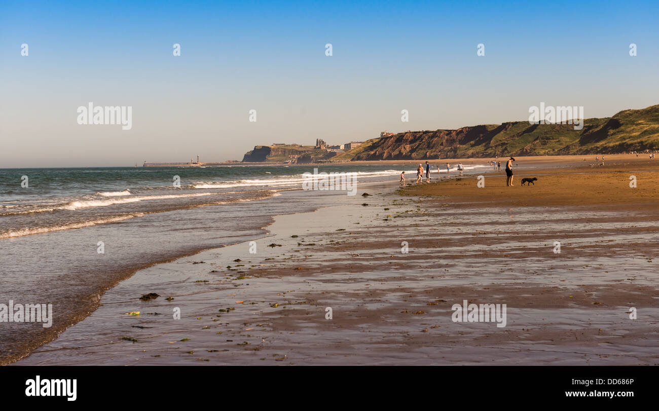 Menschen auf Whitbys Strand an einem sonnigen Sommertag in der Nähe von Whitby, North Yorkshire, UK Stockfoto