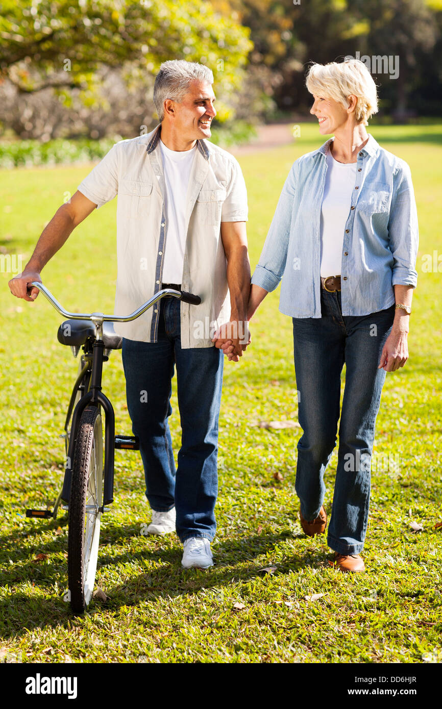 schönes älteres Paar, die ein Fahrrad im Park, die Hand in Hand gehen Stockfoto