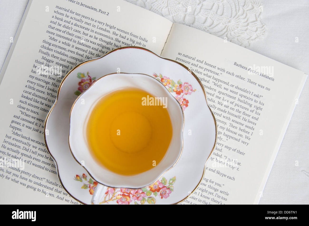 Eine Tasse Tee sitzt oben auf ein offenes romantischen Roman/Buch Stockfoto