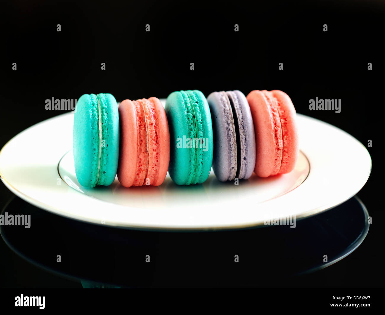 Bunte Makronen Cookies auf den weißen Teller auf dem schwarzen Hintergrund Stockfoto