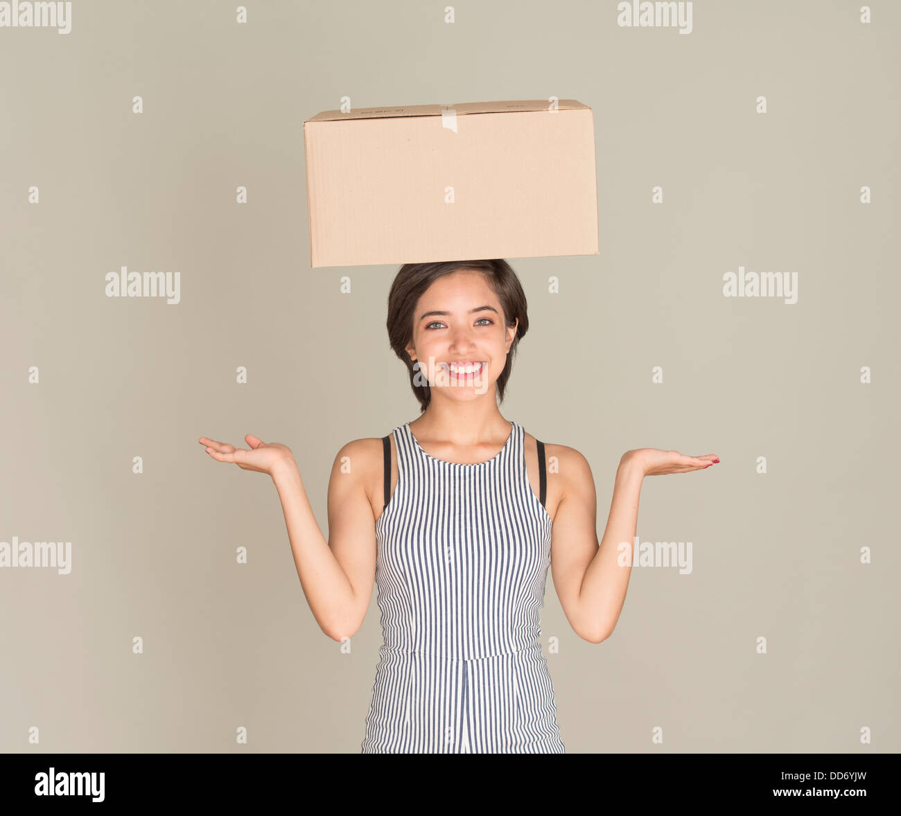 Junge Frau glücklich Gleichgewicht Karton auf dem Kopf Stockfoto