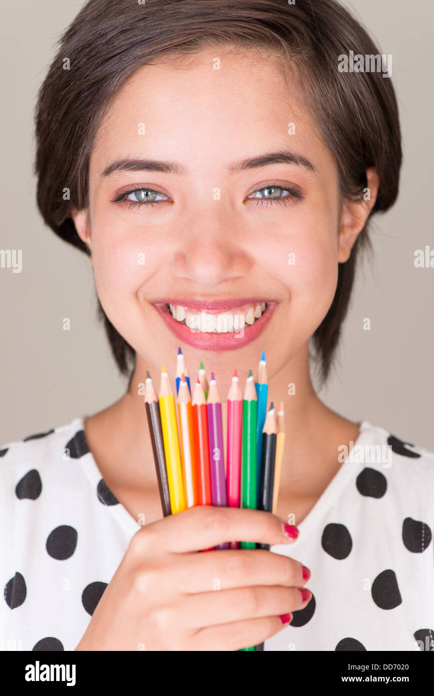 Schöne junge Frau multirassische Lächeln auf den Lippen und zeigt einen Satz Buntstifte Stockfoto