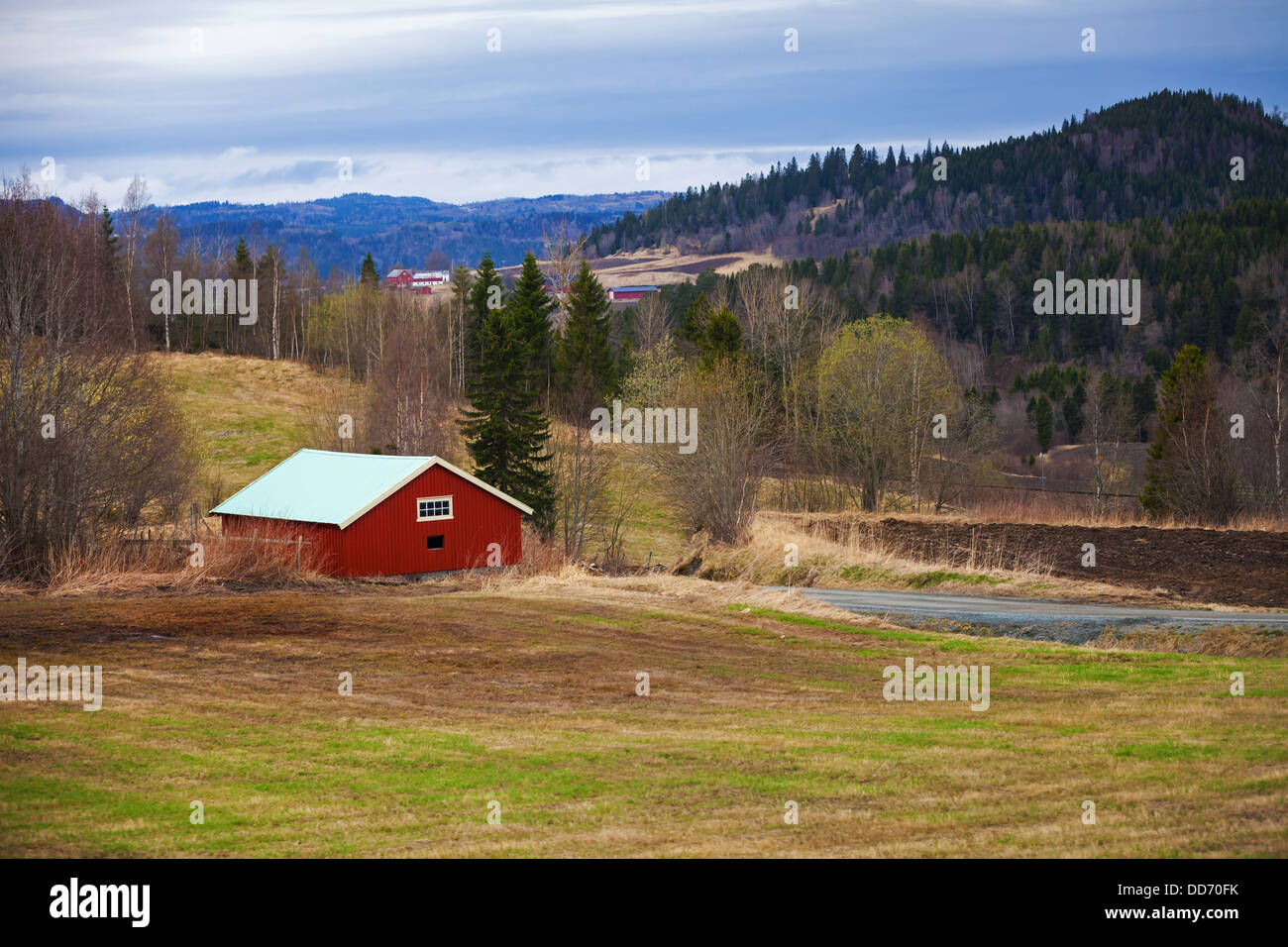 Frühling, leere ländlichen norwegischen Landschaft mit roten Holzhäusern und Wald auf Hügeln Stockfoto