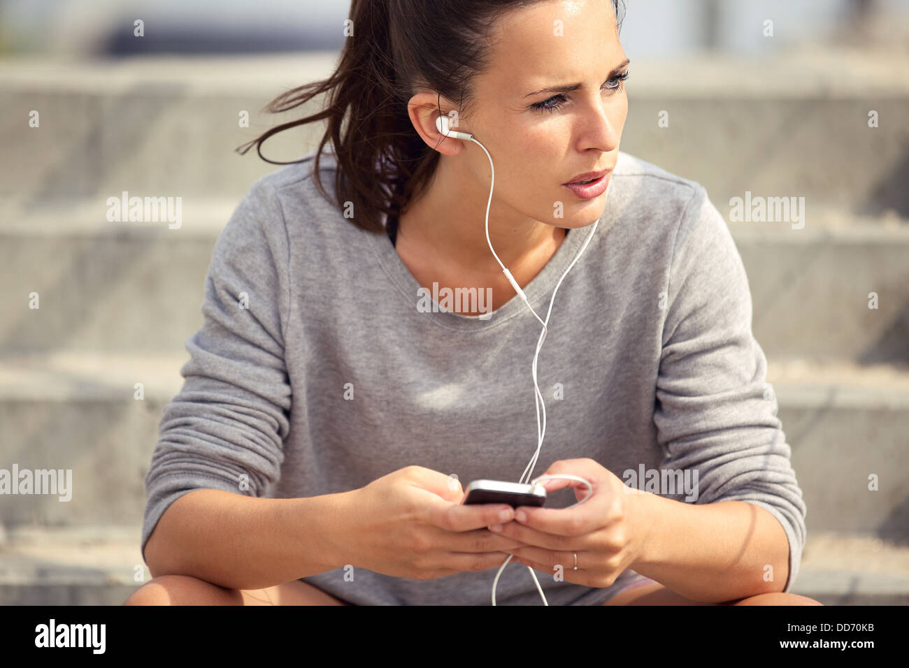 Junge Sportlerin Rast- und anhören von MP3-Musik im freien Stockfoto