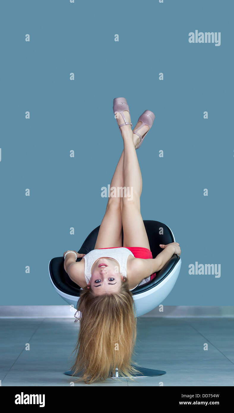 Junge attraktive Blonde Mädchen auf Stuhl liegend auf den Kopf gestellt Stockfoto