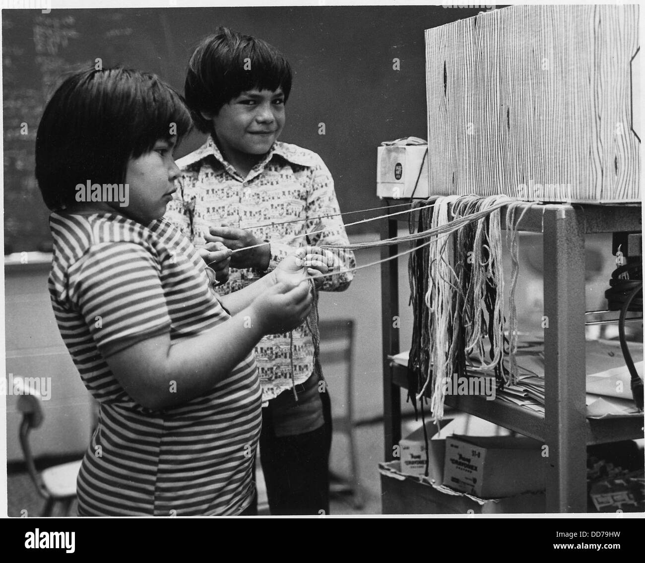 Cherokee-Kinder, die Garne weben, zeigen traditionelle Fertigkeiten, die über Generationen weitergegeben wurden. Die Aktivität spiegelt das kulturelle Erbe und die Handwerkskunst der Cherokee wider. Stockfoto