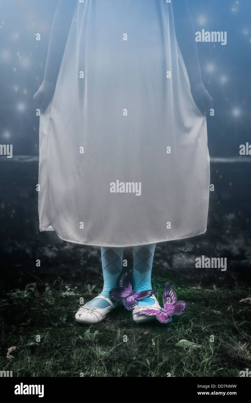 ein Mädchen in einem weißen Nachthemd draußen in der Nacht mit zwei Schmetterlinge auf die Füße Stockfoto