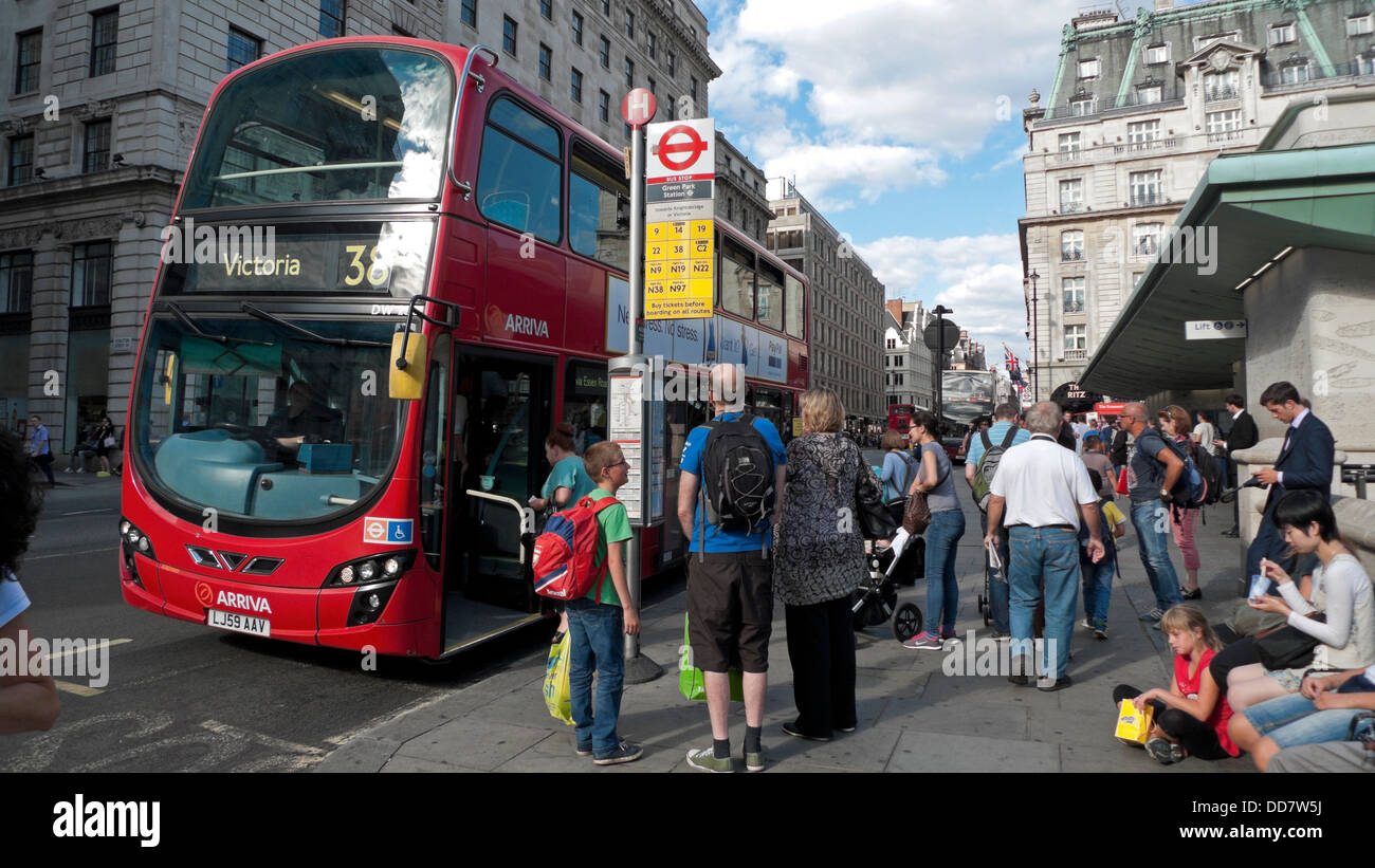 Menschen stehen an einer Bushaltestelle und Passagiere einsteigen in einen Bus Victoria 38 am Green Park London England UK KATHY DEWITT Stockfoto