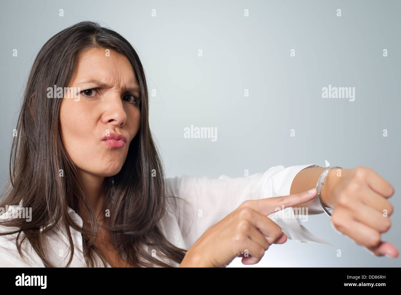 Gereizte Geschäftsfrau Tippen auf ihre Uhr und Stirnrunzeln wie sie gehalten wird warten auf einen Termin von einem unpünktlich Ende Client Stockfoto