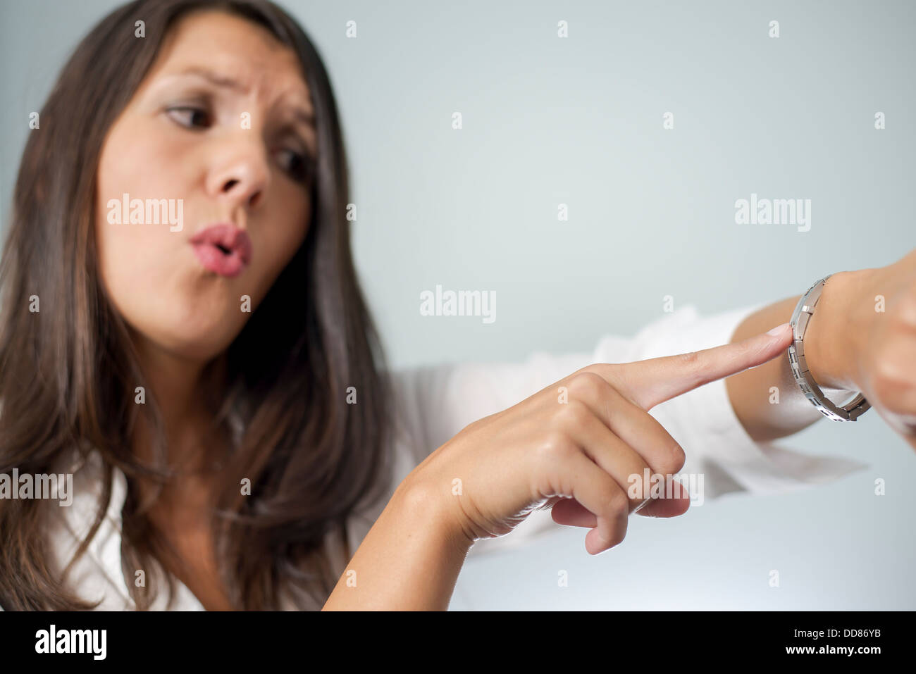 Gereizte Geschäftsfrau Tippen auf ihre Uhr und Stirnrunzeln wie sie gehalten wird warten auf einen Termin von einem unpünktlich Ende Client Stockfoto