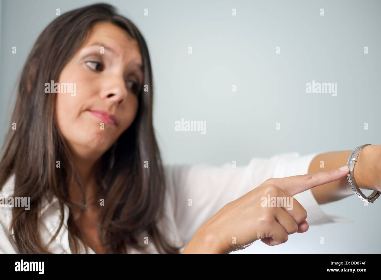 Gereizte Geschäftsfrau Tippen auf ihre Uhr und Stirnrunzeln wie sie gehalten wird warten auf einen Termin von einem unpünktlich Ende Client Stockfoto