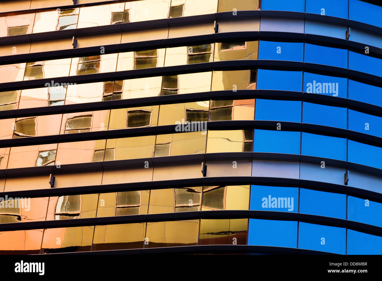 Abstrakte architektonischen Hintergrund. Eine moderne Glasstruktur mit Reflexionen von einem warmen gefärbt, Gebäude und klarer blauen Himmel. Stockfoto