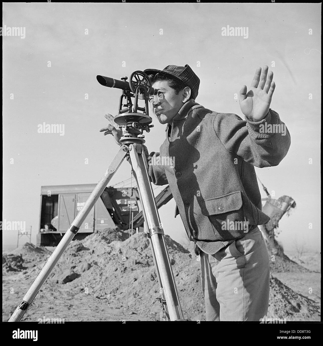 Im Granada Relocation Center in Amache, Colorado, wird ein junger Nisei beobachtet, der ein Vermessungsinstrument betreibt. Dieser historische Ort war ein japanisch-amerikanisches Internierungslager aus dem Zweiten Weltkrieg, und das Bild zeigt die Beteiligung japanisch-amerikanischer Internierter an verschiedenen Aktivitäten. Stockfoto