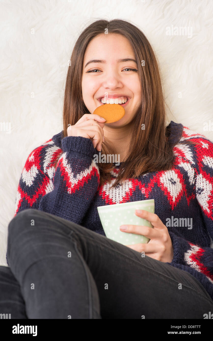 Schöne junge Erwachsene Frau hält eine Tasse heiße Schokolade und Essen ein Lebkuchen-bisquit Stockfoto