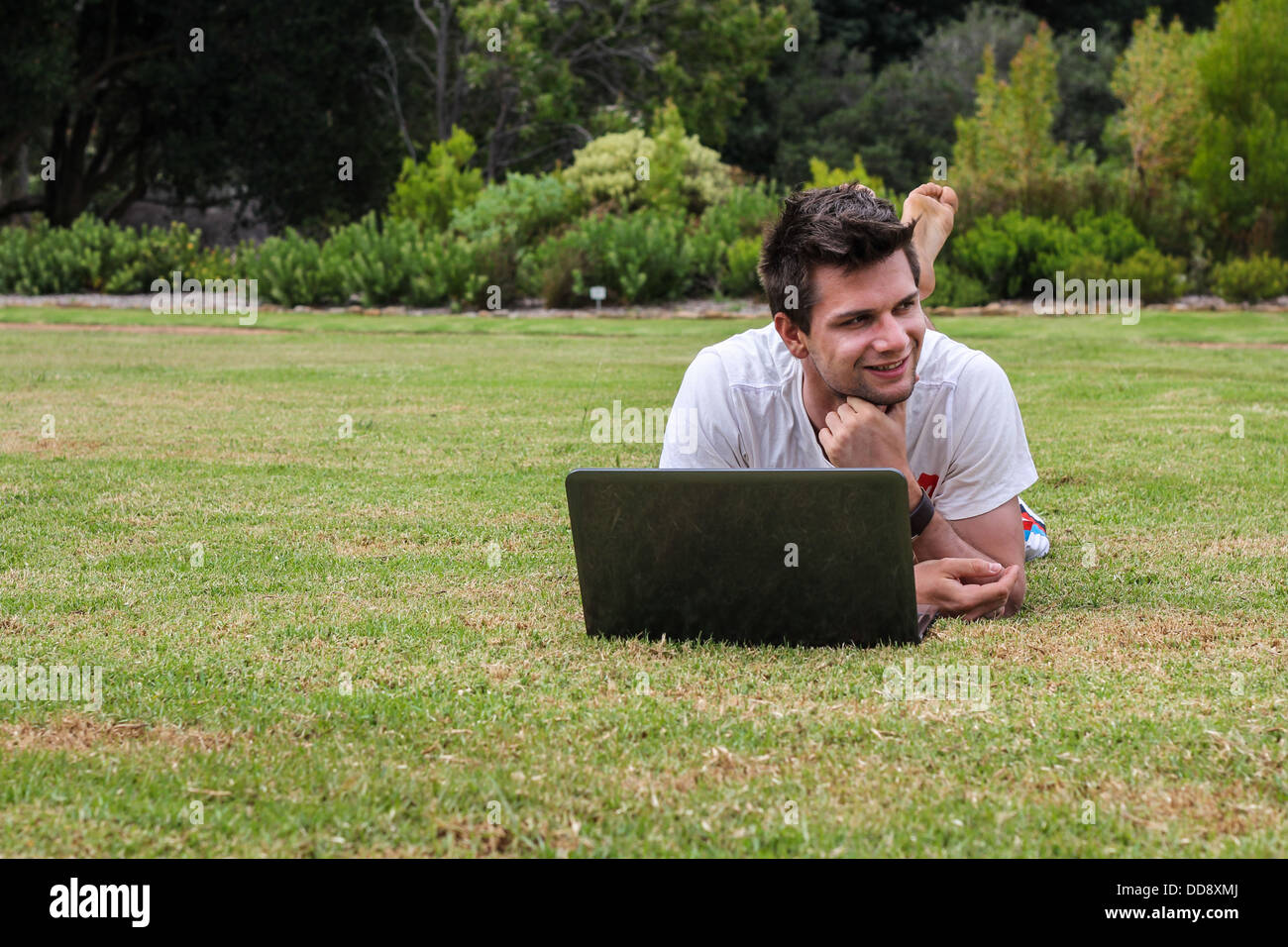 Mann arbeitet auf Notebook draußen im park Stockfoto