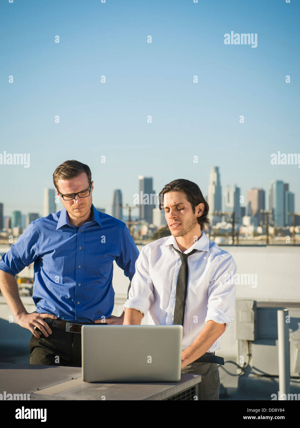Geschäftsleute, die mit Laptop auf städtischen Dach Stockfoto