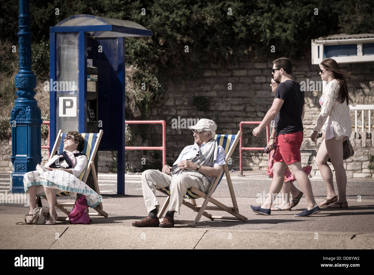 Ein paar sitzen in Liegestühlen am Meer in Bournemouth, England Stockfoto