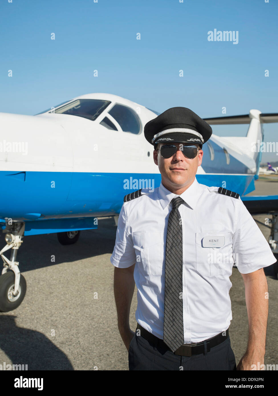 Kaukasische Pilot mit dem Flugzeug auf der Piste Stockfoto