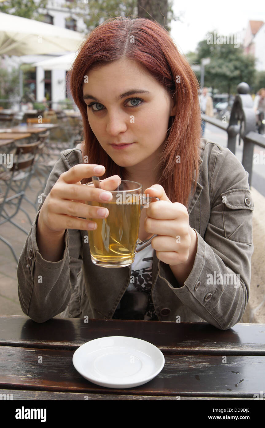 junge Frau trinkt Tee in einem Straßencafé Stockfoto