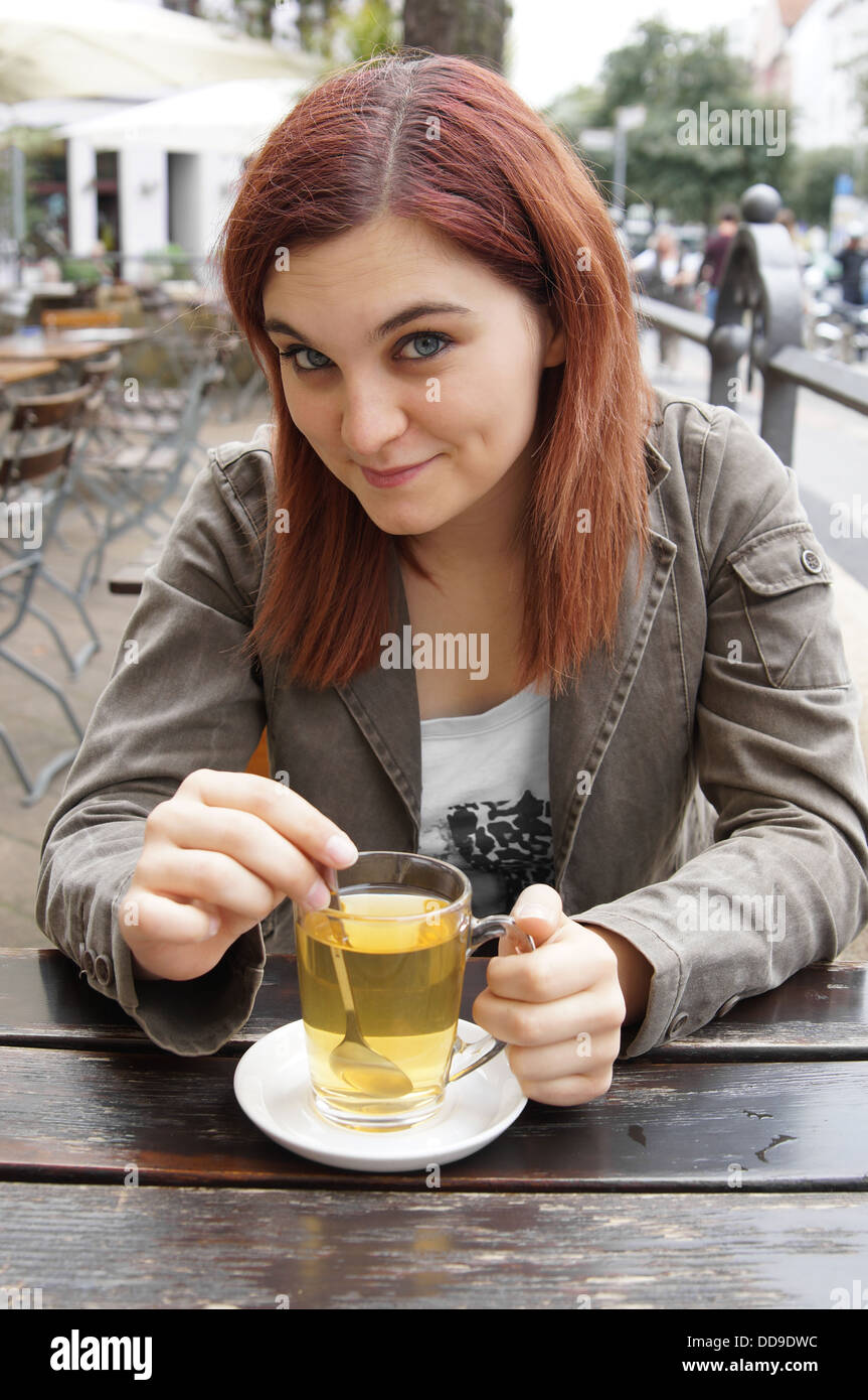 junge Frau trinkt Tee in einem Straßencafé Stockfoto