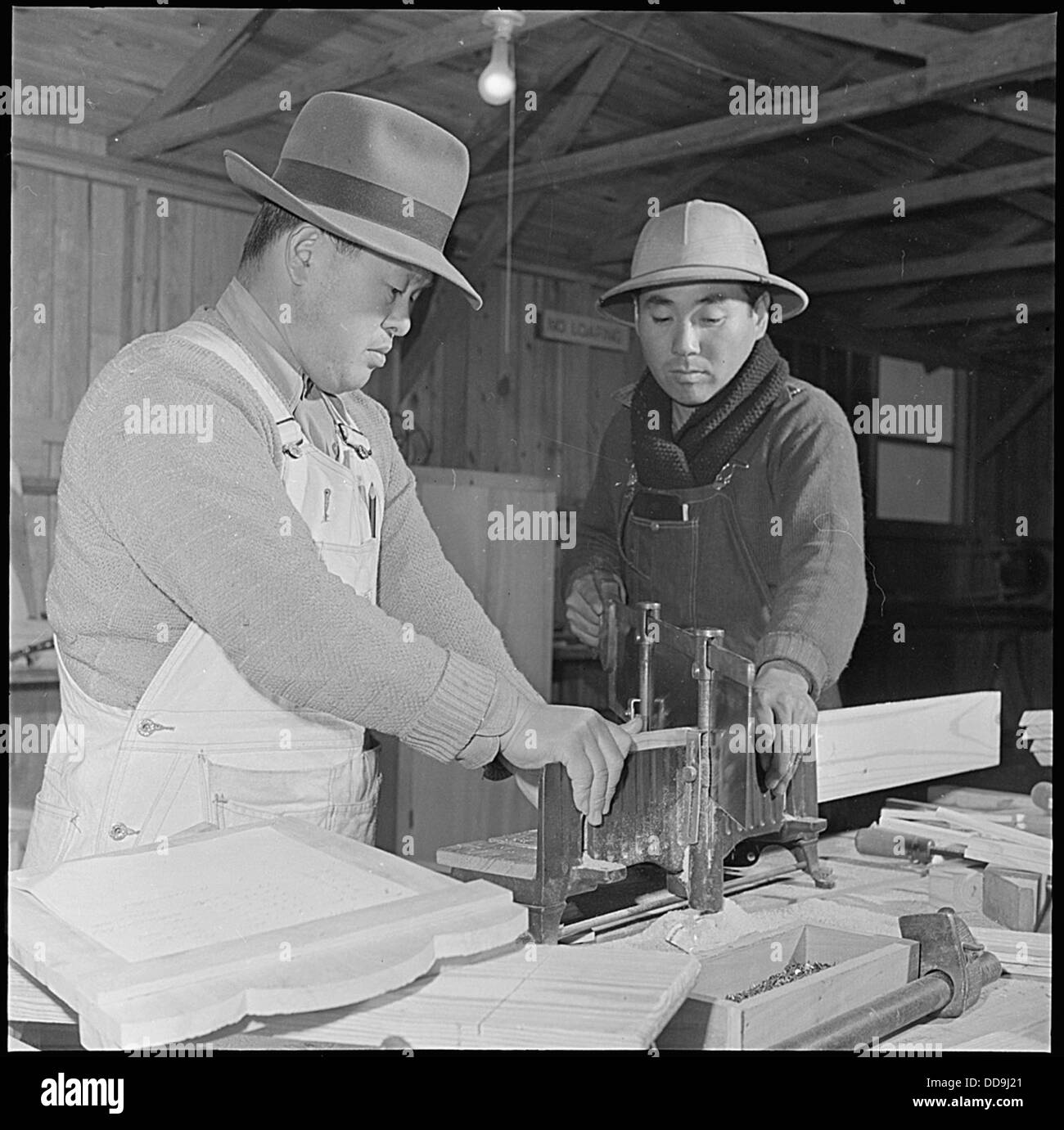 Im Inneren des Möbelgeschäfts im Jerome Relocation Center in Denson, Arkansas, werden während der Japanisch-amerikanischen Internierung Arbeiter gezeigt, die an Handwerk und Arbeit arbeiten. Stockfoto