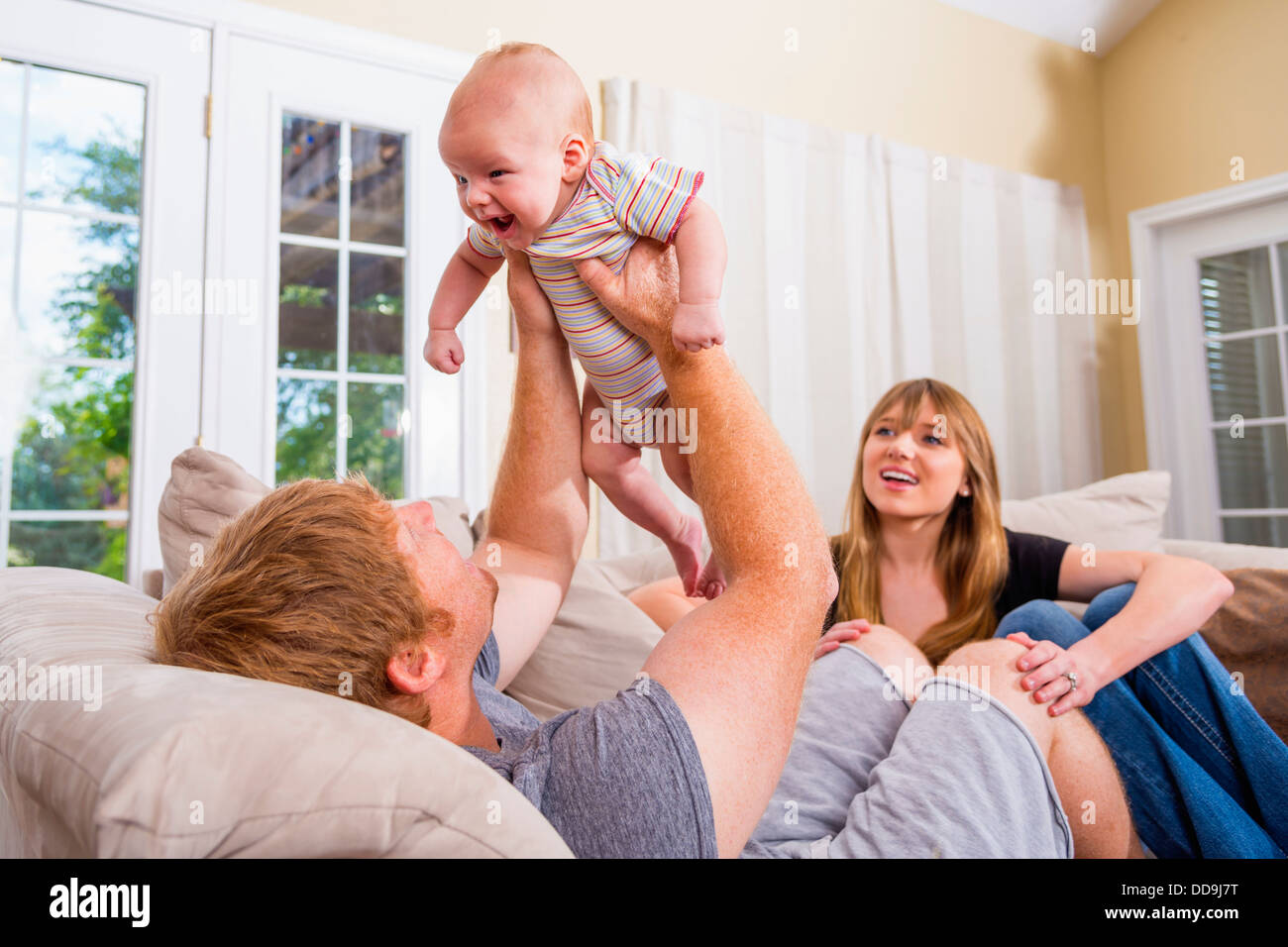 Eltern mit Baby auf Couch sitzen, Lächeln Stockfoto