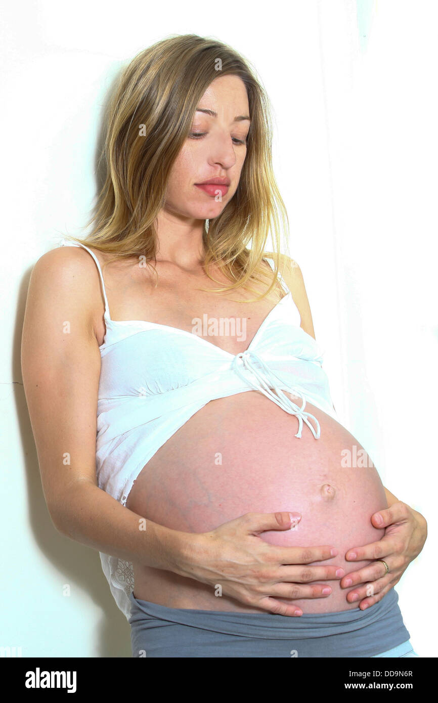 Schwangere Frau schaut ihr Bauch auf weißem Hintergrund Stockfoto