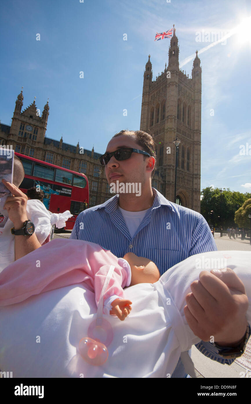 London, UK. 29. August 2013.  Ein Mann hält ein "totes" Baby während einer Protestaktion vor dem Parlament von Großbritannien ansässigen Syrern, die fordern, dass Maßnahmen gegen das Assad-Regime für Chemiewaffen Aginst Zivilisten attackiert. Bildnachweis: Paul Davey/Alamy Live-Nachrichten Stockfoto