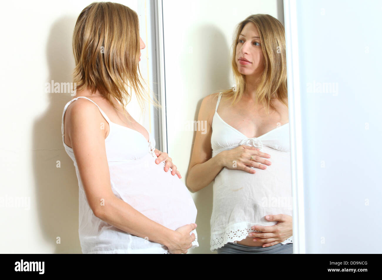 Schwangere Frau schaut ihre Reflexion in einem Spiegel Modell Release verfügbar Stockfoto