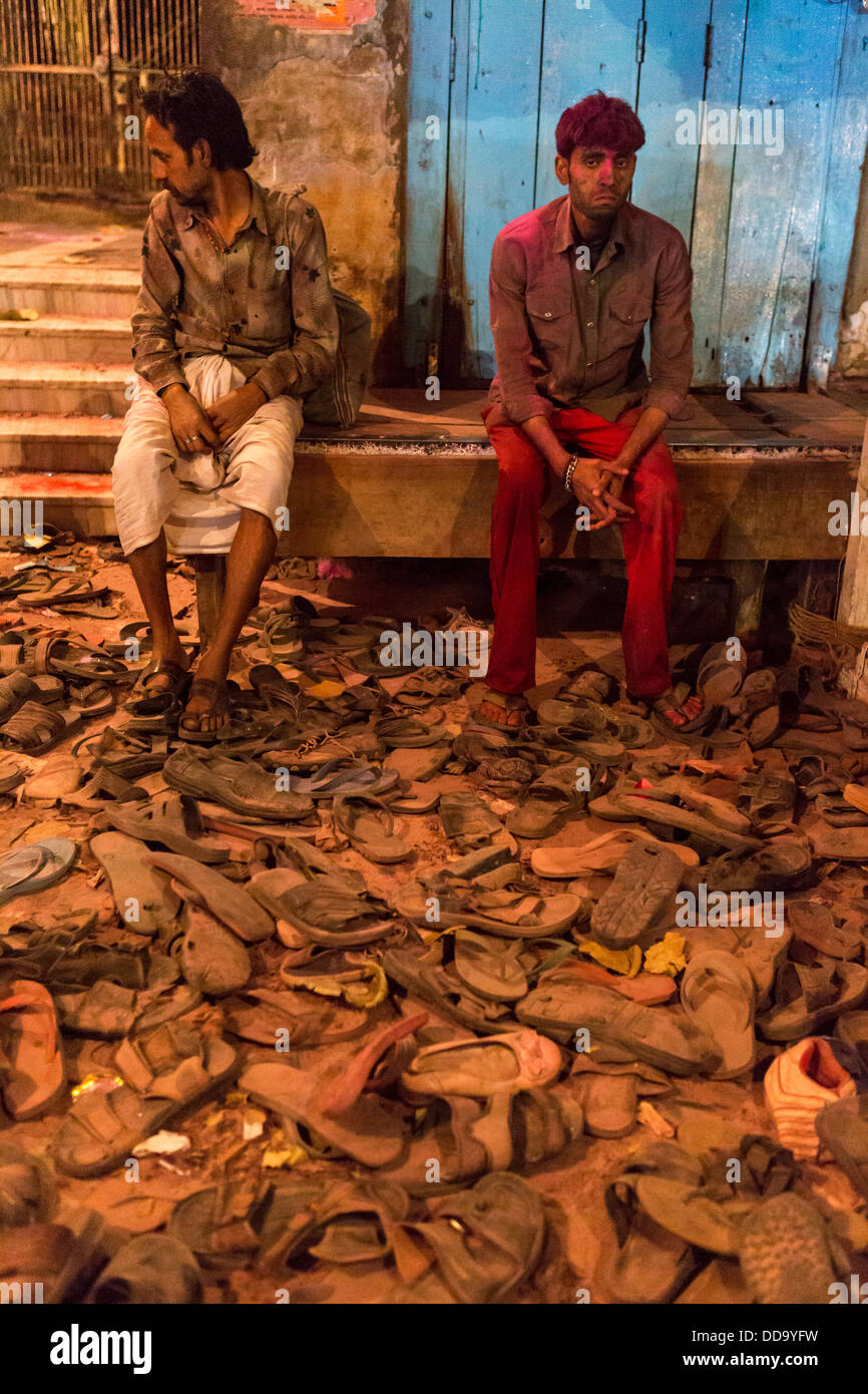 Zwei Männer in einem der Ausgänge des Tempels während der Feier des Holi ruhen. Vor ihnen, Hunderte von Schuhen verloren. Stockfoto