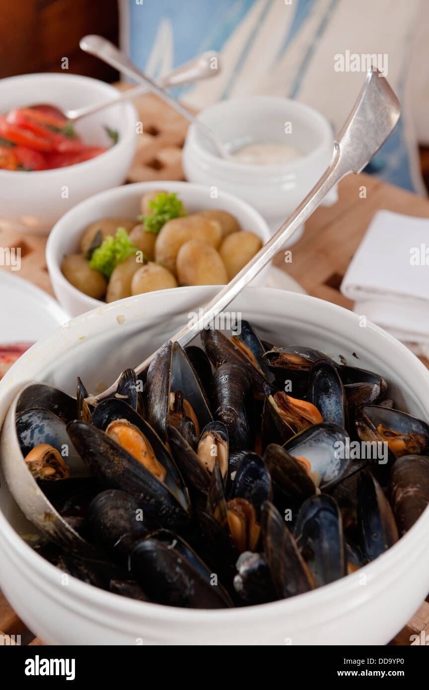 Muscheln und Kartoffeln in Schüsseln an Bord eines Bootes Stockfoto