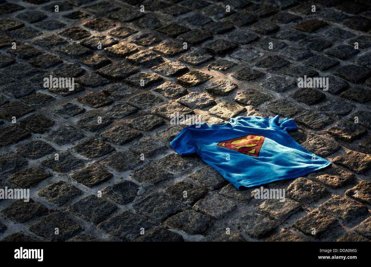 Childs Superman t shirt hell durch die Sonne auf einer gepflasterten Straße. Großbritannien Stockfoto