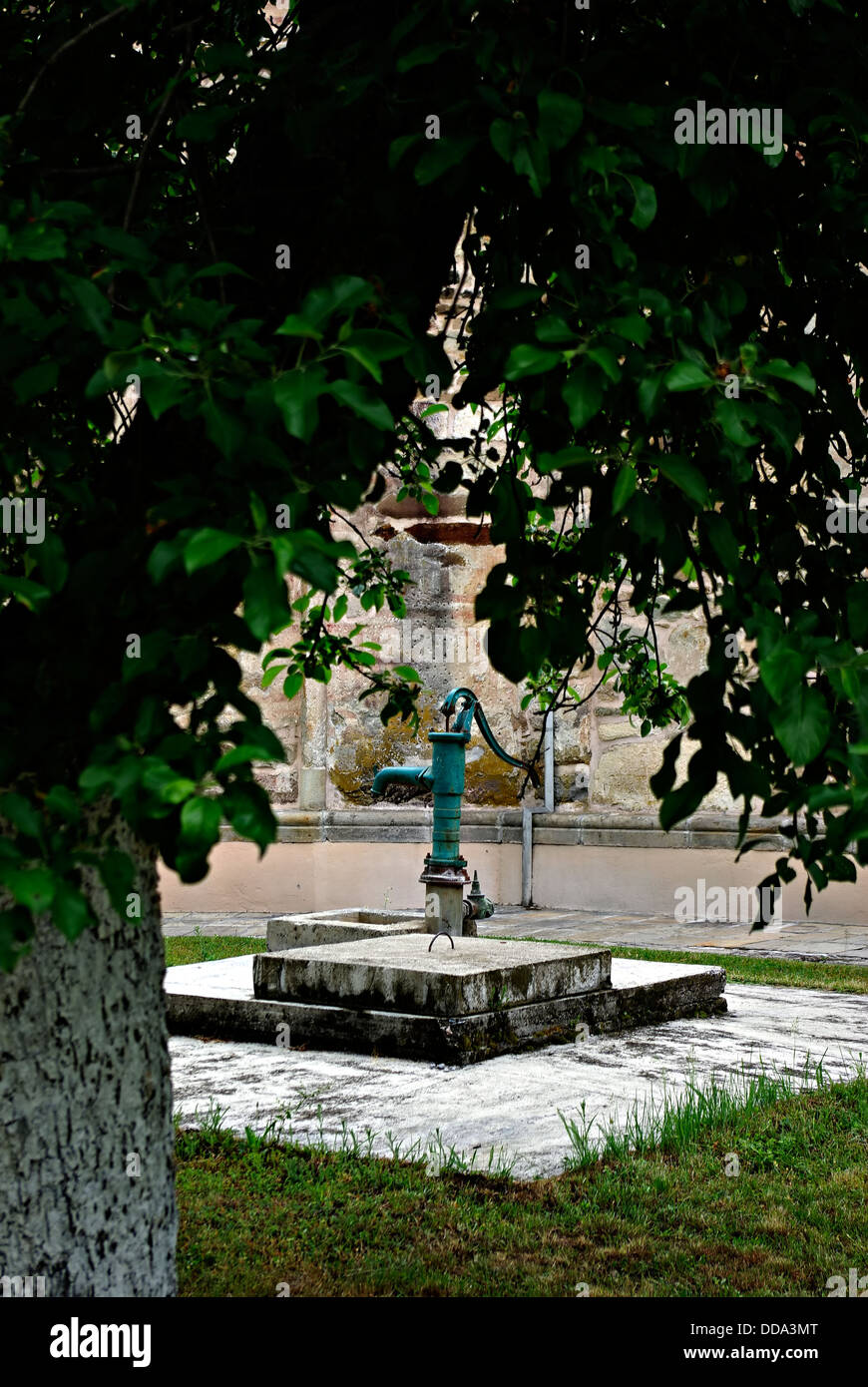 Hand-Wasserpumpe auf dem Friedhof auf einem konkreten Sockel im Schatten eines Baumes. Stockfoto