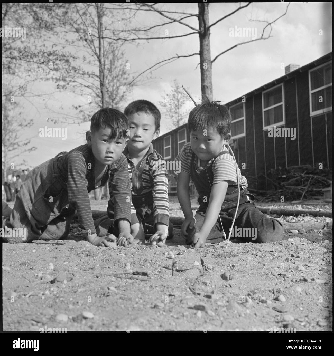 Im Rohwer Relocation Center in McGehee, Arkansas, werden japanische amerikanische Kinder während ihrer Internierung im Zweiten Weltkrieg beim Spielen von Marmor beobachtet Stockfoto