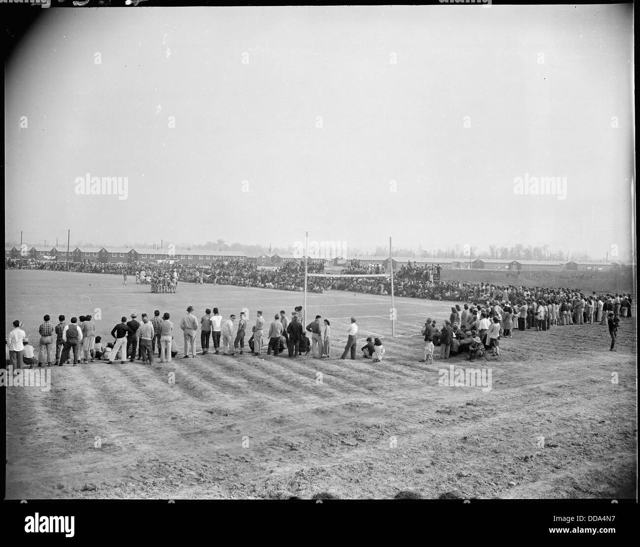 Im Rohwer Relocation Center in McGehee, Arkansas, zieht ein Fußballspiel einen Teil der Menge an und bietet einen Moment der Freizeit und der Community-Aktivität während einer schwierigen Zeit in der Geschichte der USA. Stockfoto