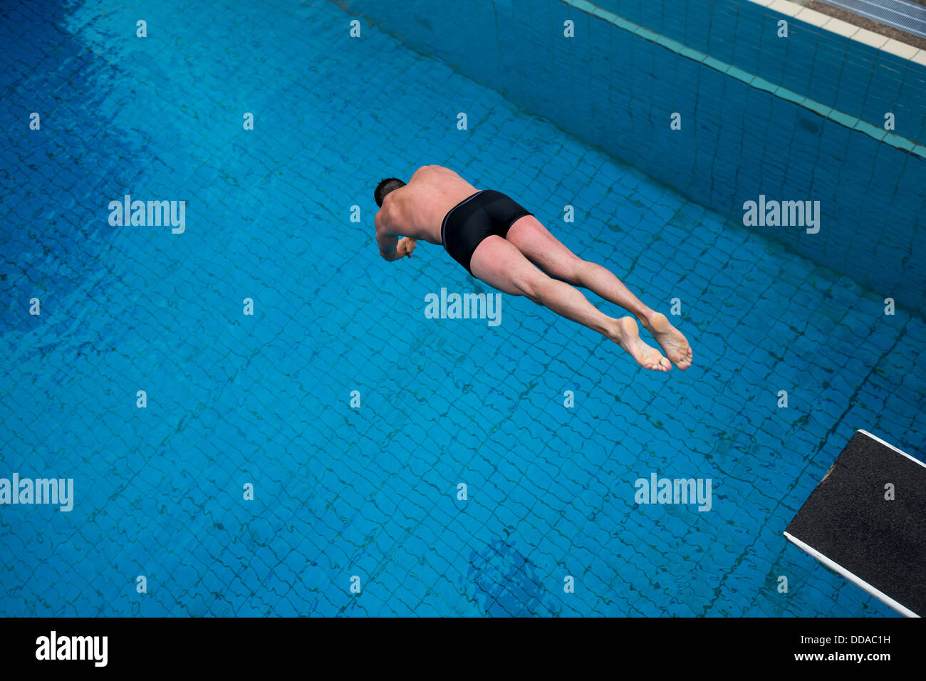 Mann springt vom Sprungbrett im Schwimmbad Stockfoto