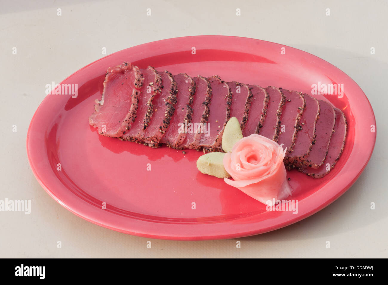 Gebratene Ahi Thunfisch selten serviert auf einem roten Teller garniert mit Wasabi und eingelegtem Ingwer rose Stockfoto