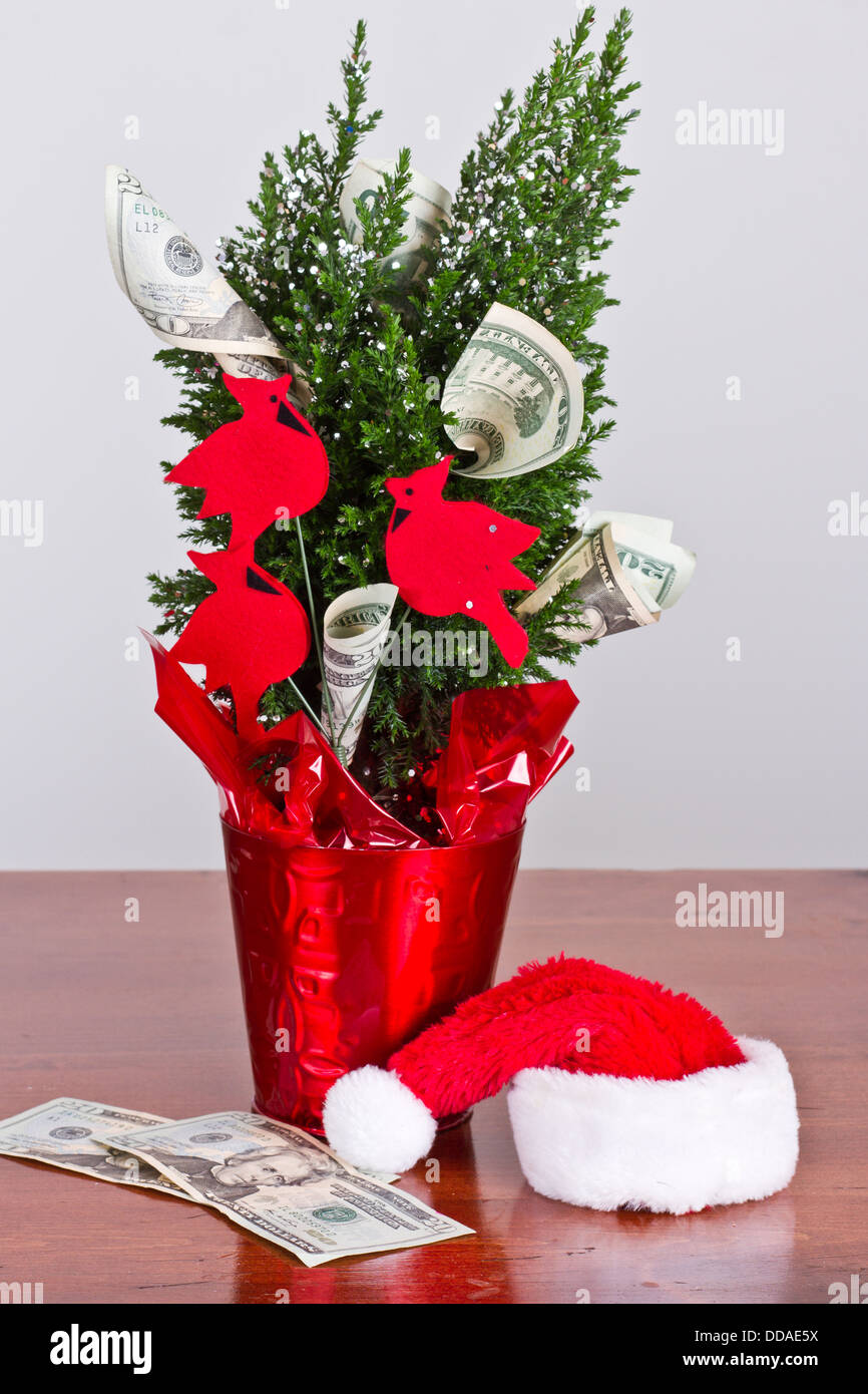 kleiner Weihnachtsbaum mit 20-Dollar-Scheine wachsen aus ihm heraus und eine Weihnachtsmütze Stockfoto
