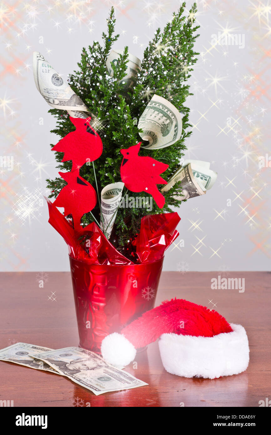kleiner Weihnachtsbaum mit 20-Dollar-Scheine wachsen aus ihm heraus und eine Weihnachtsmütze Stockfoto