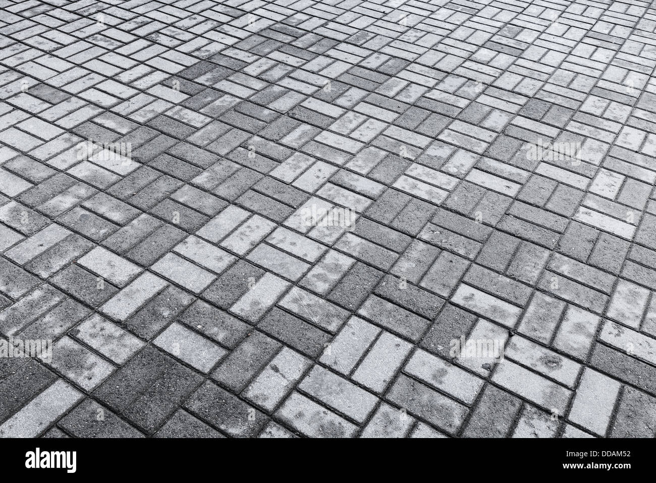 Hintergrundtextur von grauen modernen gepflasterten Straße mit nassen und trockenen Steinen Muster Stockfoto