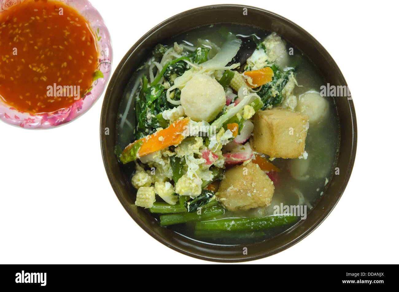 asiatische Suppe mit Schweinefleisch, Frikadellen, Ei und Gemüse in die Schüssel und Chili-Sauce mischen Stockfoto