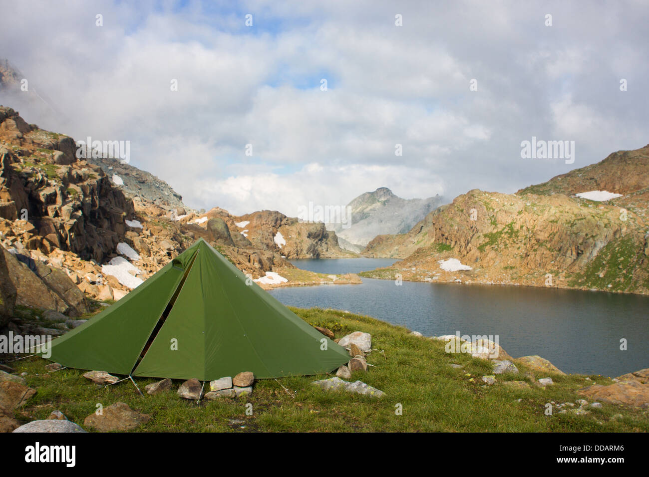 Wandern in den Bergen; ein grünes Zelt in der Nähe von einem schönen Bergsee Stockfoto