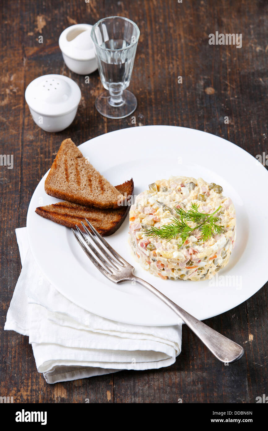 Russische traditionelle Salat Olivier mit Erbsen auf hölzernen Background Stockfoto