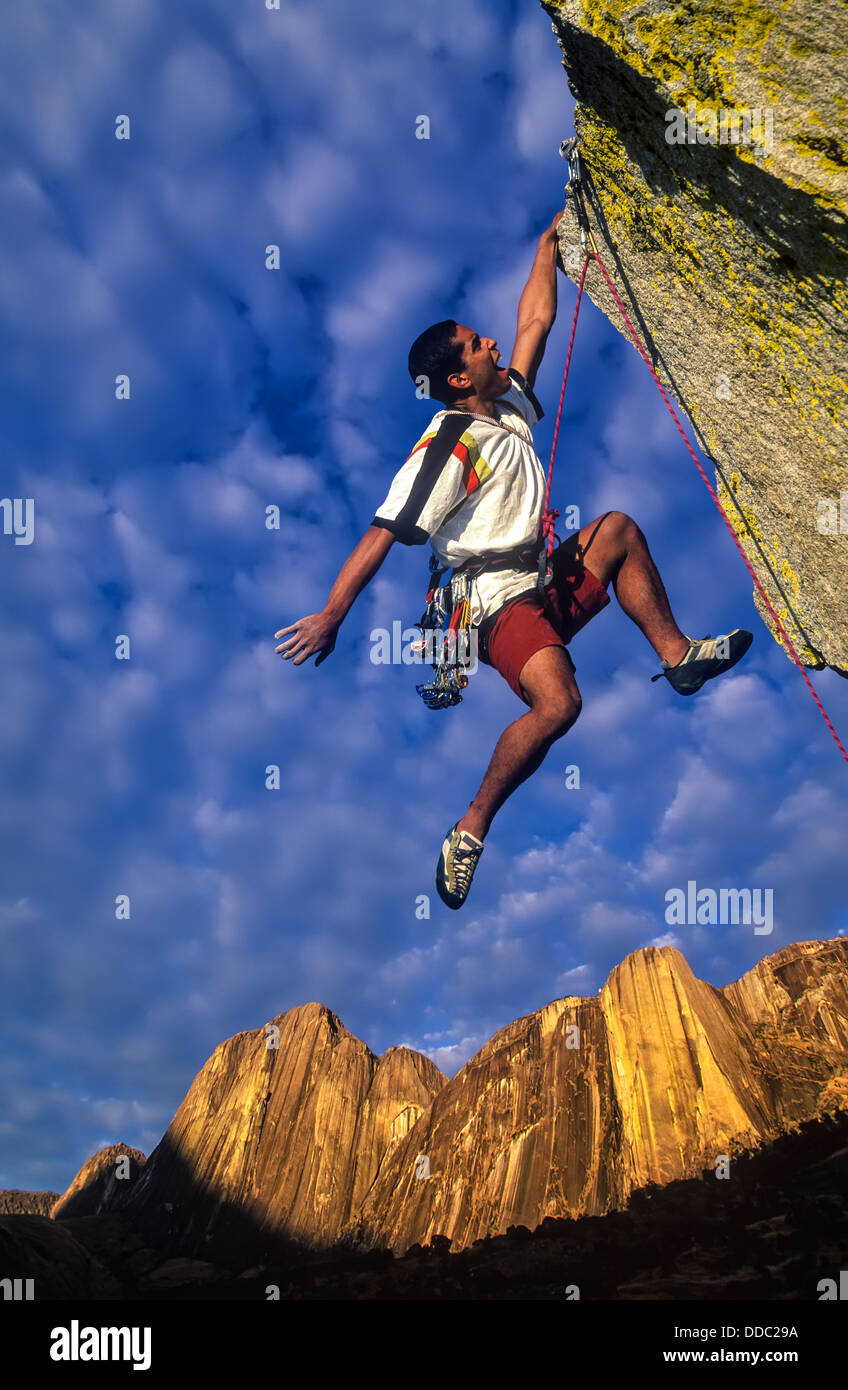 Rock Climber Kämpfe bis zum Gipfel des einen herausfordernden Höhepunkt als Gewitterwolken bauen hinter ihm. Stockfoto