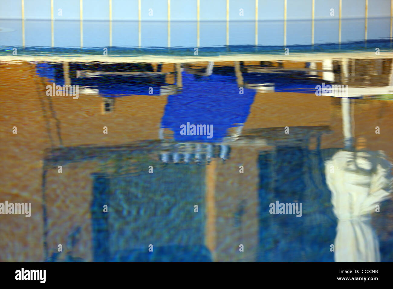 Reflexion des blauen Liegestühle und Sonnenschirm in einem Schwimmbad Stockfoto