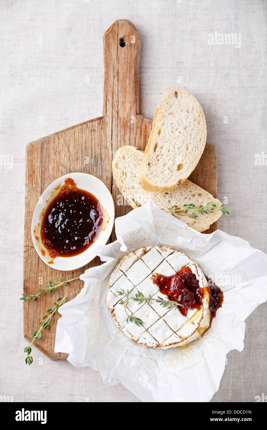 Gebackener Camembert Käse mit Thymian und geröstetem Brot auf Holzbrett Stockfoto