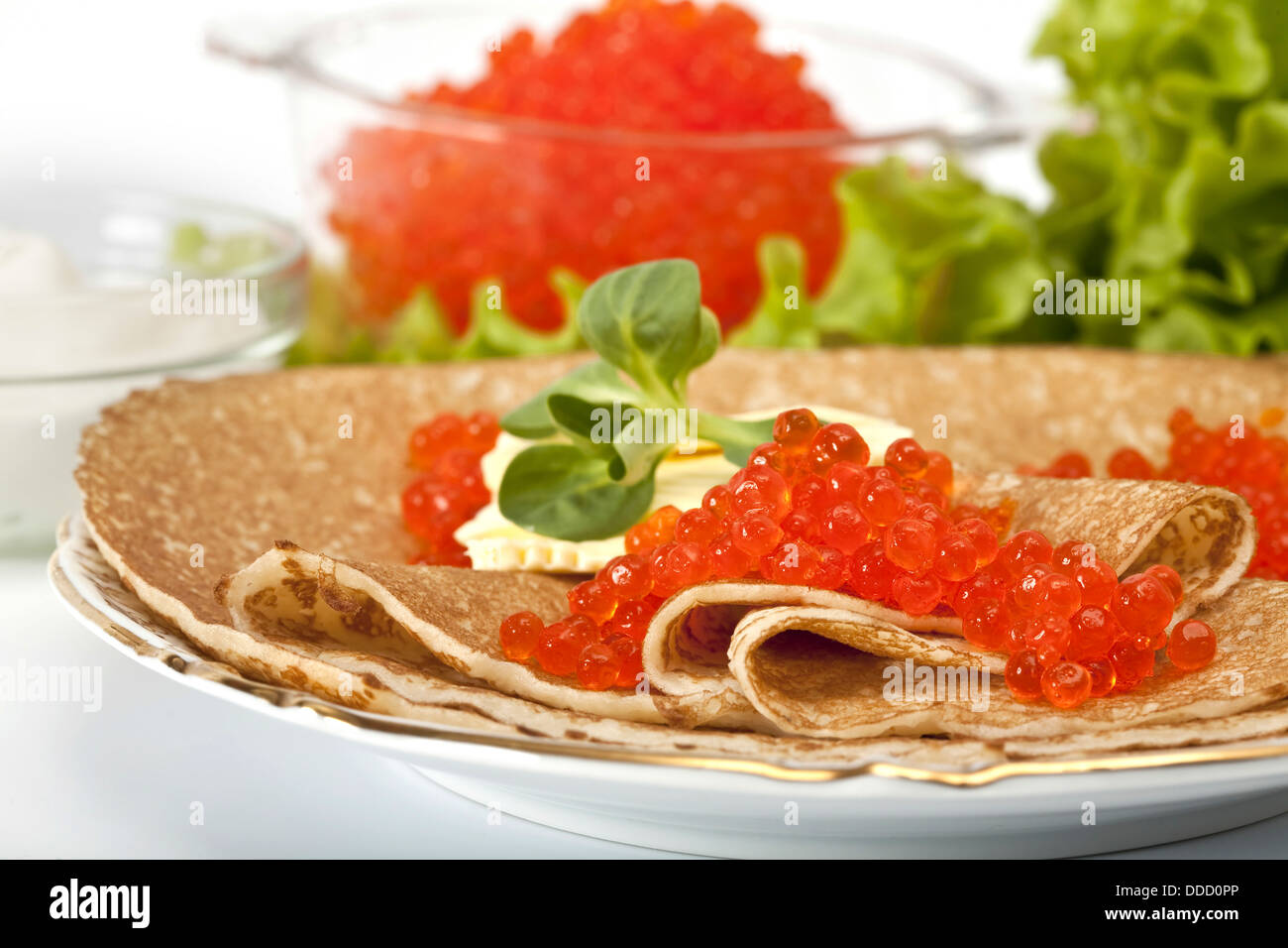 Gedeck serviert: Pfannkuchen mit rotem Kaviar, Sauerrahm und Grüns Stockfoto