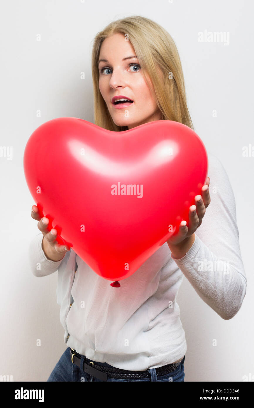 Überrascht kaukasischen Frau hält einen rotes Herz-Ballon Stockfoto
